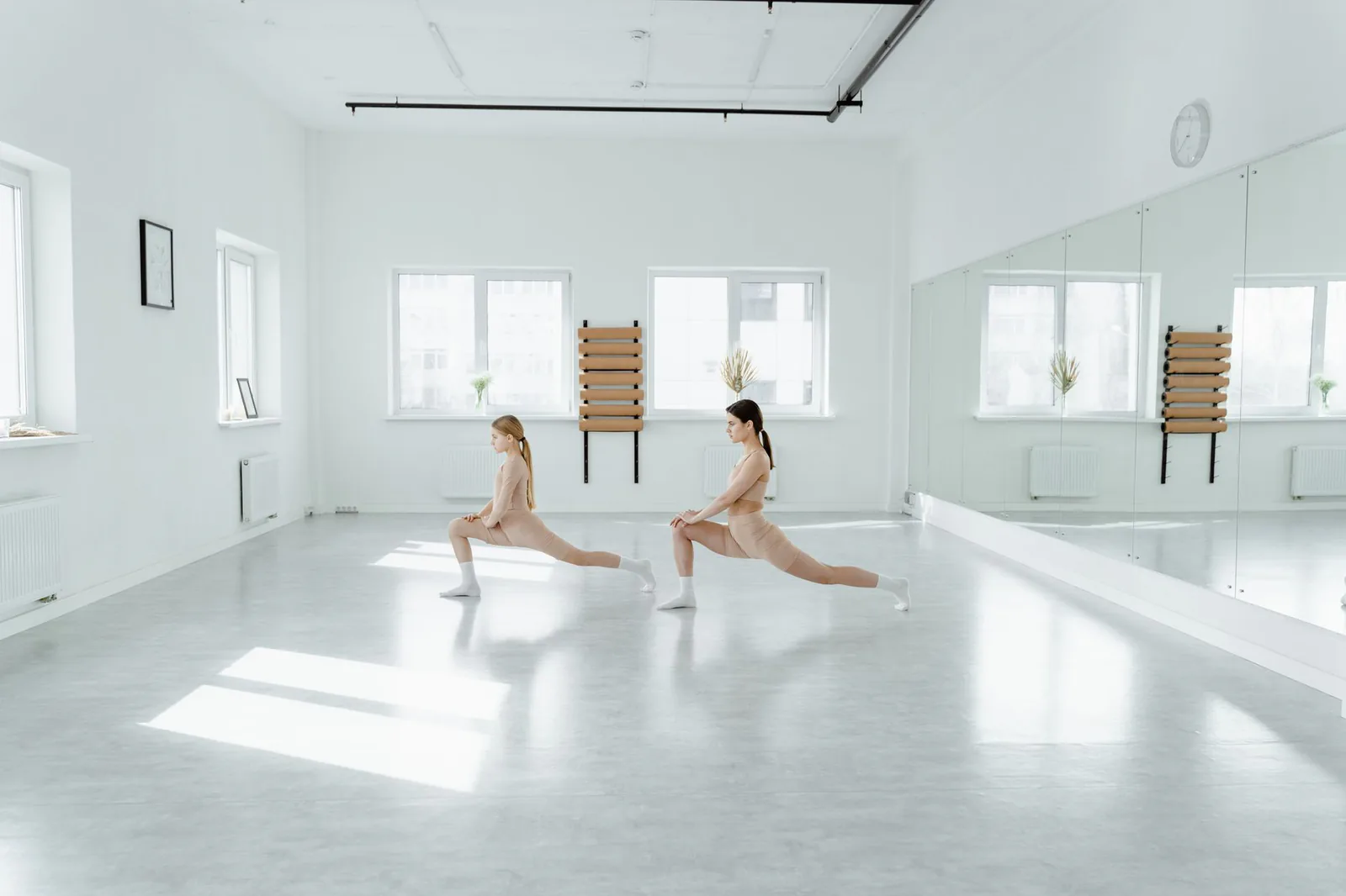 Two students holding a low lunge pose side by side