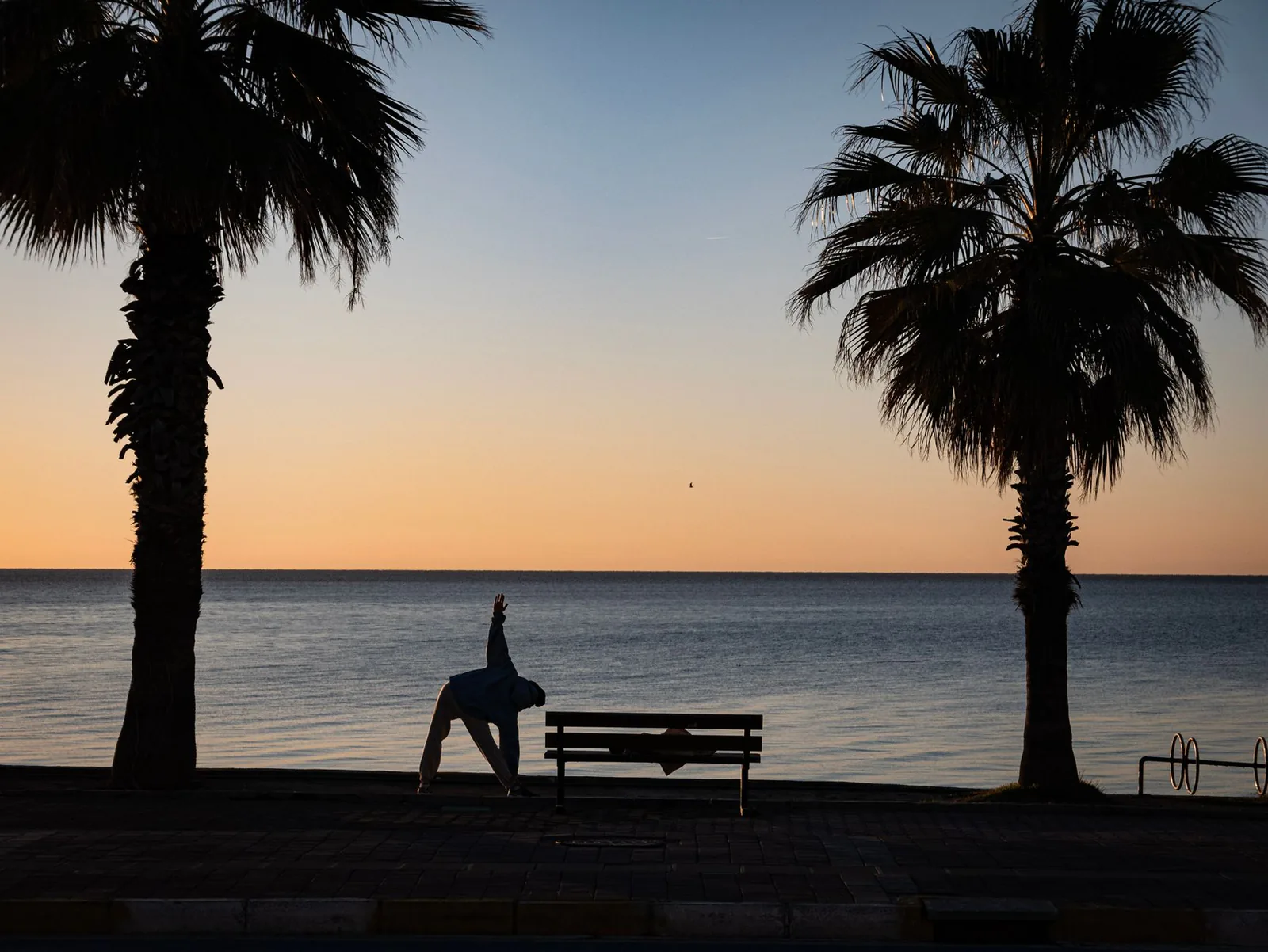 A traveler practicing a sunrise stretch beside the sea